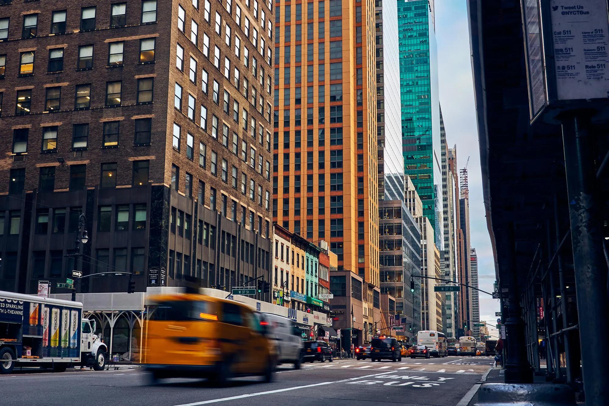 A yellow taxi driving through Midtown Manhattan in New York City