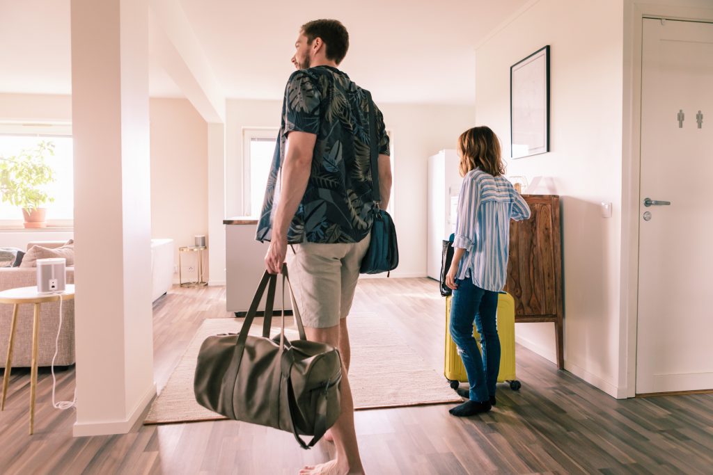Smiling couple carrying bags while moving into their new apartment, for an article on 'How to Market Your Apartment for Rent