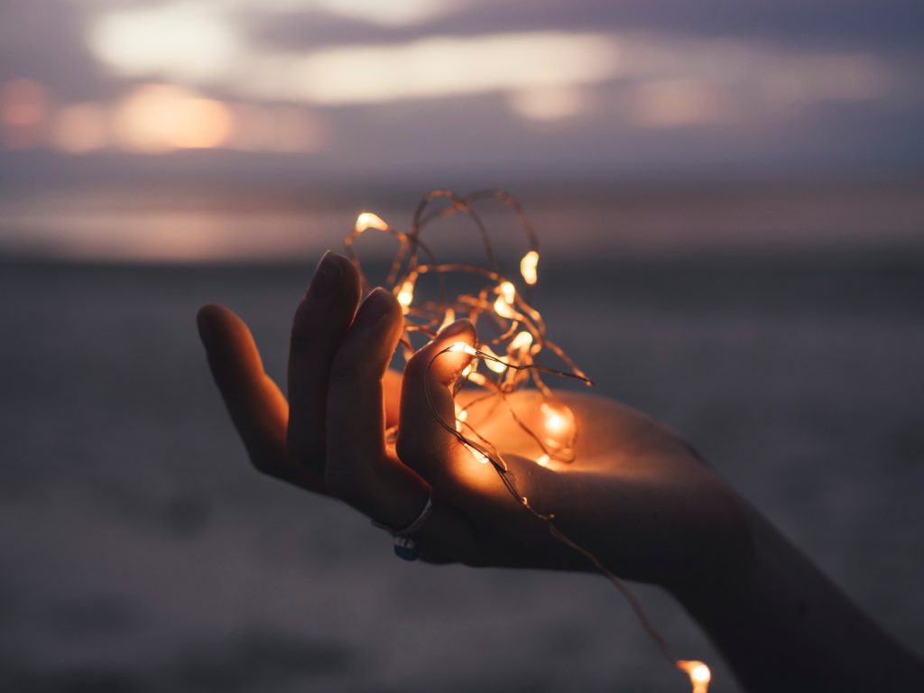 Hand holding a garland of warm-toned fairy lights 