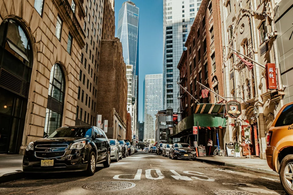 Vehicles navigating through the bustling streets between towering buildings in one of the best neighborhoods in Manhattan.