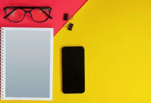 Beside Eyeglasses and Binder Clips on Yellow and Red Background