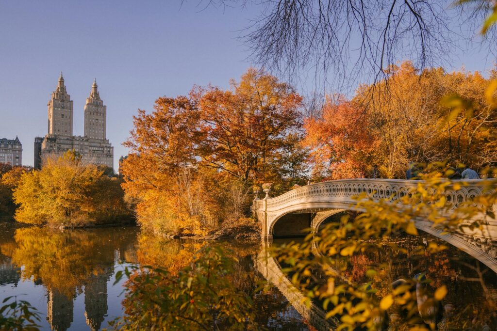 Bow Bridge crossing calm lake in autumn park