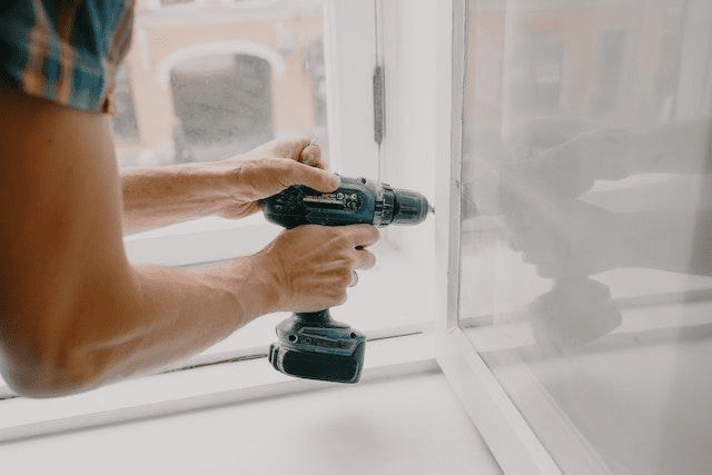  A person repairing a window with a drill.