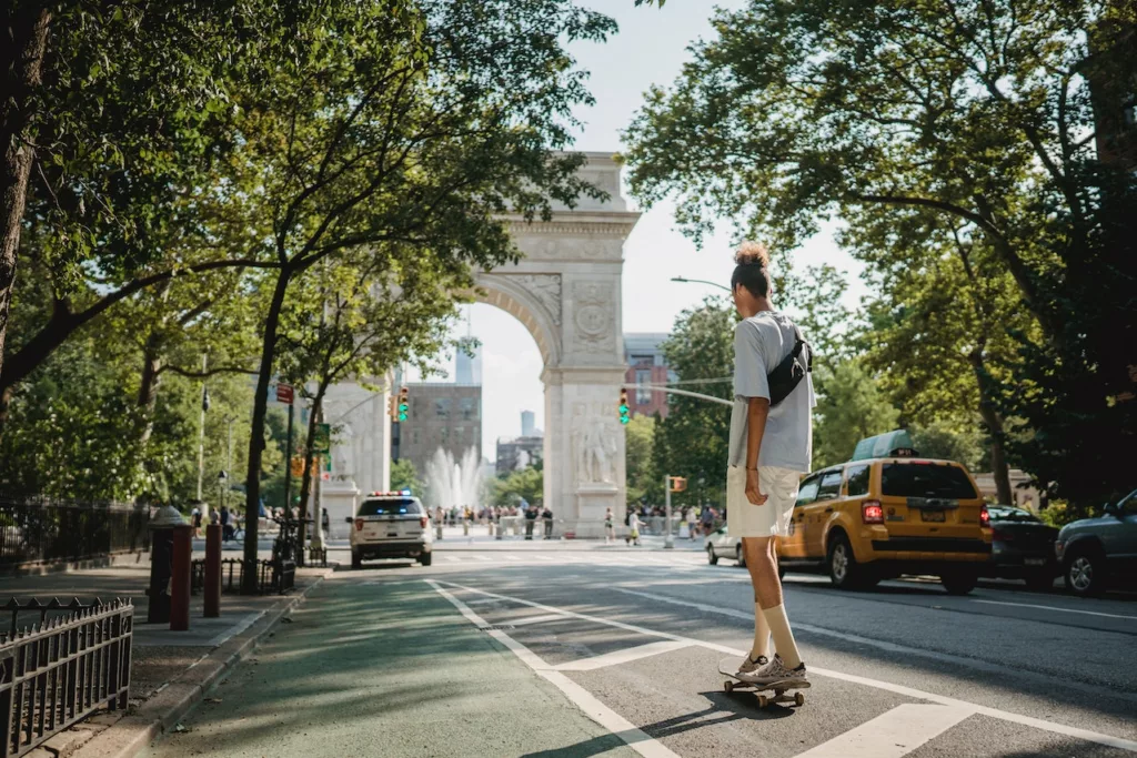 Unrecognizable sporty guy riding skateboard on city street in daylight NYC - Calculate How Much Do You Need To Make To Afford (X) Rent Article