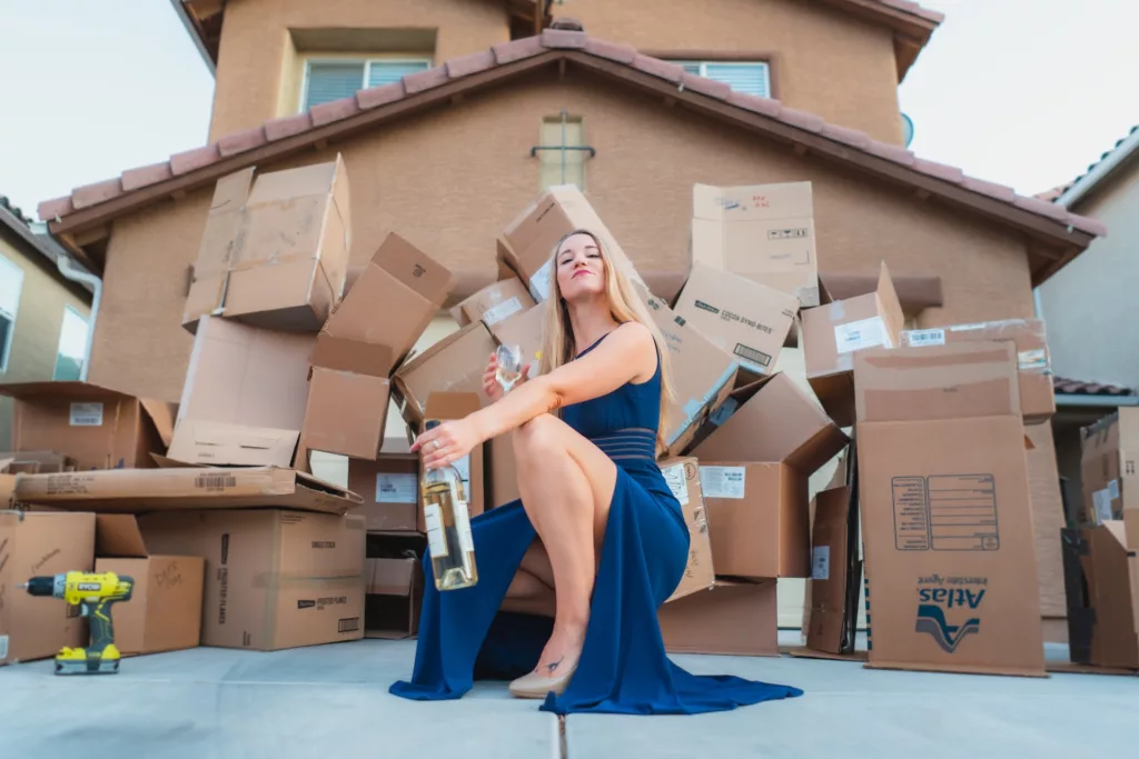 Woman in a blue dress confidently carrying a brown moving box, preparing for a big move.