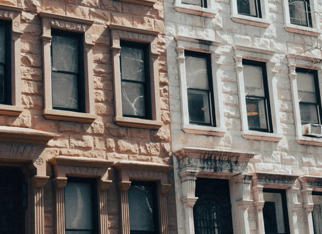 Image of a traditional brownstone building with detailed stone work around the windows and an ornate cornice, typical of New York City architecture, possibly reflecting the type of apartments listed on websites for finding housing in NYC.