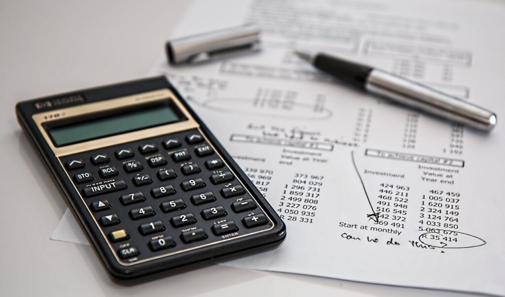 A black calculator near a ballpoint pen on white printed paper.