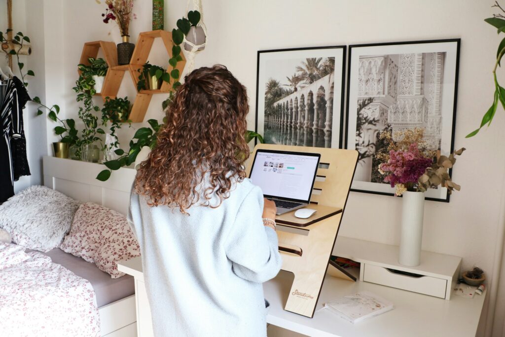 Person working on a laptop at a standing desk in a cozy, furnished apartment, with plants and decorative wall art in the background, accompanying the article titled 'Standout Features to Watch for in Furnished Apartments.