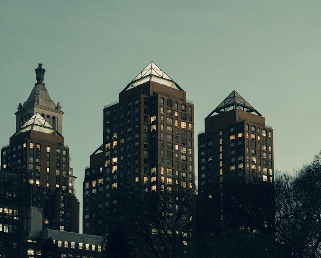 High-rise apartment buildings in NYC at dusk with illuminated windows.