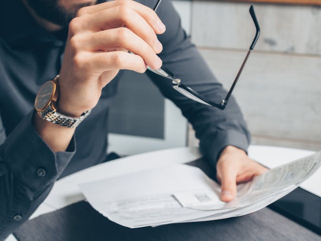 Man in a business shirt holding glasses while reviewing documents