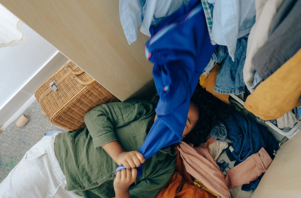 Person sorting through a messy pile of clothes on the floor.